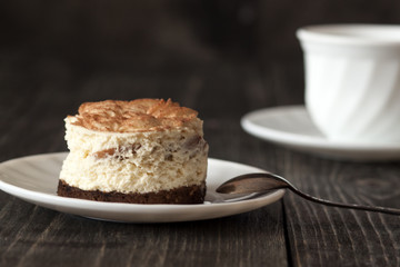 Tiramisu cake on a white saucer and a cup of black coffee
