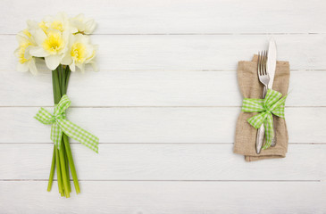 Spring table setting.Fork a nd knife,empty space   and spring flowers on white wooden board.Cutlery set with space for text