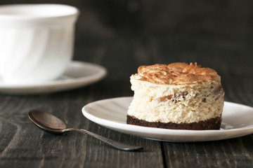 Tiramisu cake on a white saucer and a cup of black coffee