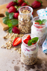 Homemade healthy breakfast with homemade baked granola, fresh strawberry and yogurt on stone or concrete table. Copy space.