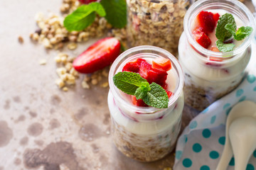 Homemade healthy breakfast with homemade baked granola, fresh strawberry and yogurt close-up on stone or concrete table.