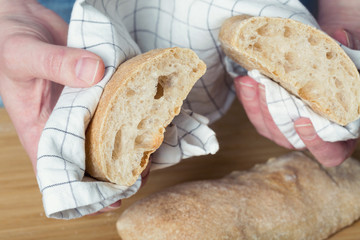 Female hands holding homemade ciabatta bread on wooden background