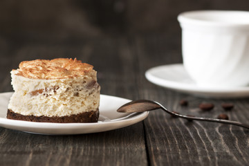 Tiramisu cake on a white saucer and a cup of black coffee
