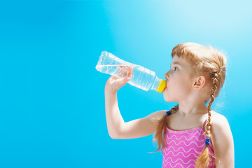 Little girl in swimsuit drinking water