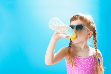 Little girl in swimsuit drinking water