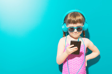 Charming girl in swimsuit using phone with headphones