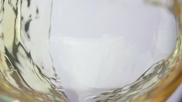 Wave of white wine curls in a glass