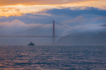 The Golden Gate bridge in San Francisco at sunset with mist rolling in