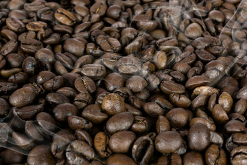 Coffee production background - many hot roasted brown beans and smoke in close-up as a texture  (high details).