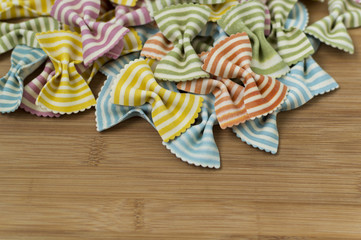 Colorful raw bow-tie  pasta on wooden background with copy space