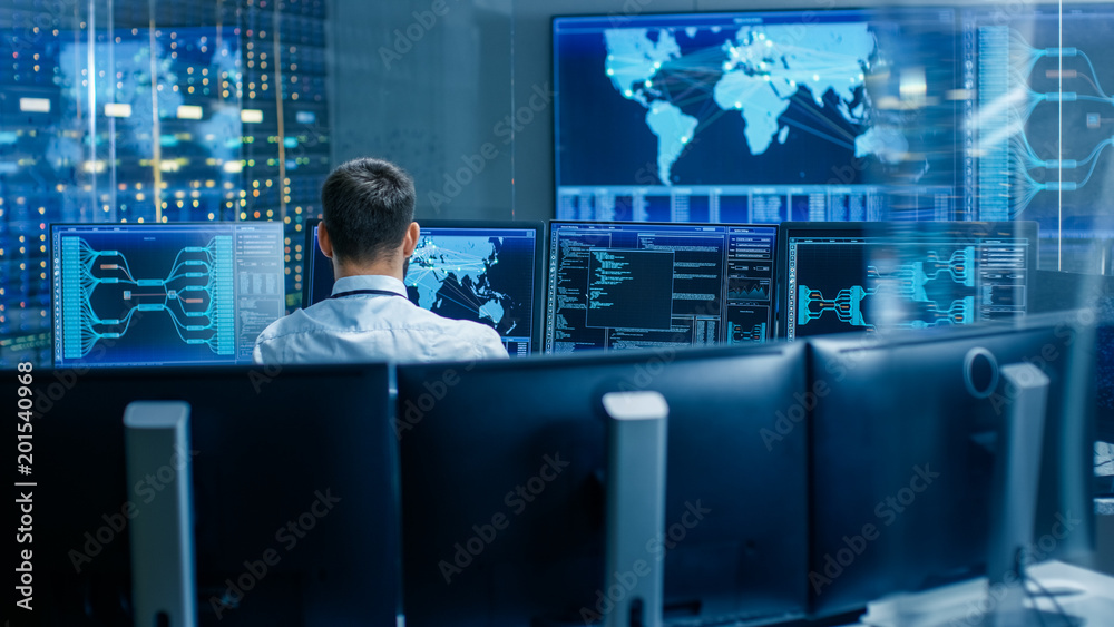 Poster Back View in the System Control Center Operator Working. Multiple Screens Showing Technical Data.
