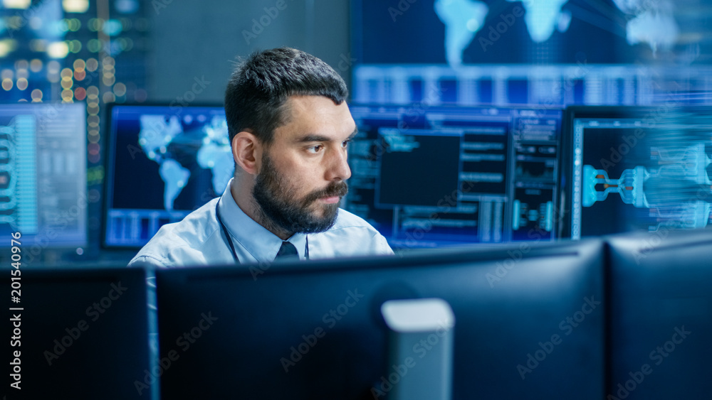 Poster In the Monitoring Room Technical Operator Attentively Monitors Stability of the System. He's Surrounded By Screens Showing Technical Data.