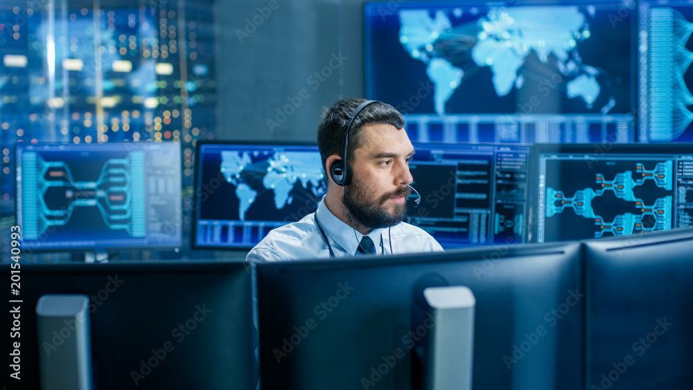 Poster System Control Room Dispatcher Talks into Headset. He Controls Correct Work of the Facility. In the Background Multiple Monitors Show Technical Data.