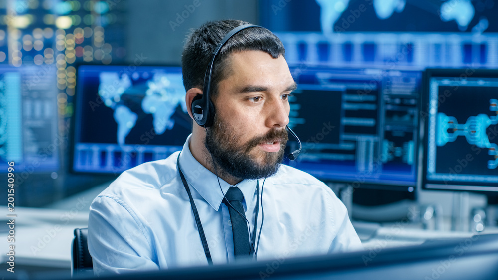 Fototapete System Control Room Dispatcher Talks into Headset. He Controls Correct Work of the Facility. In the Background Multiple Monitors Show Technical Data.