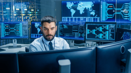 Monitoring Room Technical Operator Observes System Stability. He's Surrounded By Screens Showing...