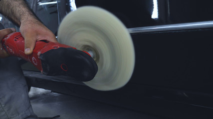 An employee is a professional who polishes a black car, repairs cars, car wash, service.