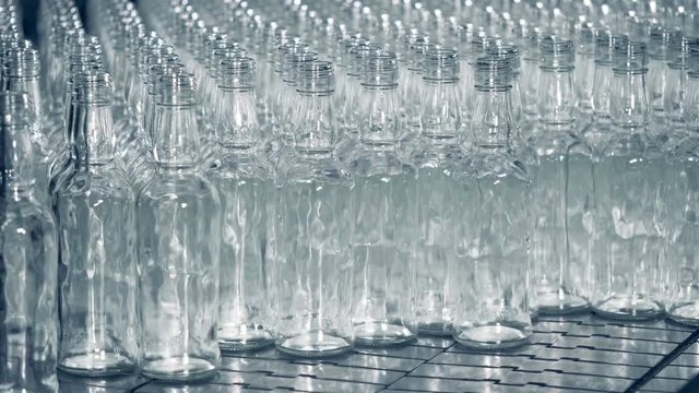 Timelapse of many glass bottles groups on a conveyor, close up.