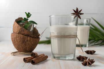 Shell of coconut and coconut milk in glass with cinnamon on wooden table.