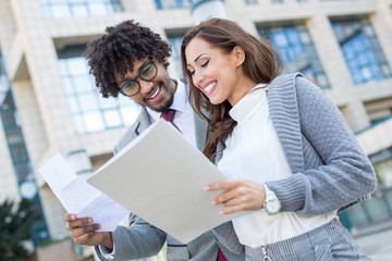 Beautiful young business couple checking some paperwork in front of the office