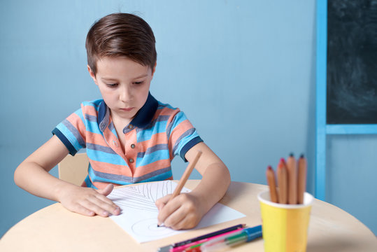 Caucasian boy spending time drawing with colorful pencils at home.