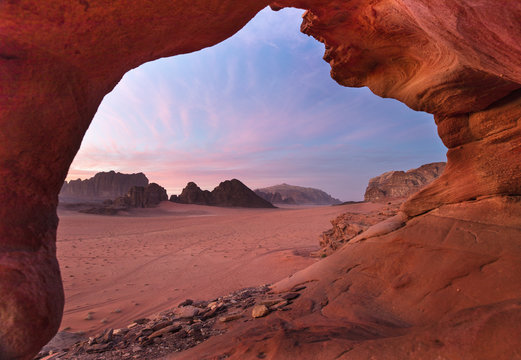 view through red stone arch to beautiful dusk in desert Wadi Rum in Jordan