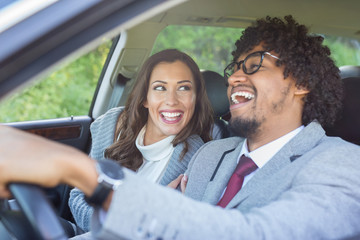 Happy young couple driving in a car while smiling