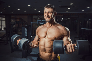 Fototapeta na wymiar european caucasian athletic man bodybuilder holding dumbell and showing his muscular arms. man doing exercise for biceps. Biceps workout clouse-up. at once two dumbbells