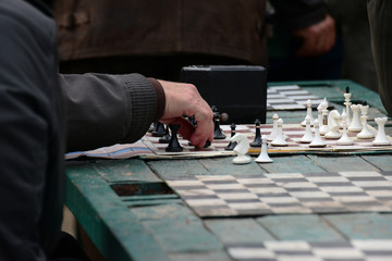 Active people in their free time on vacation with pleasure playing chess on the street. Figures and chess board close-up.
