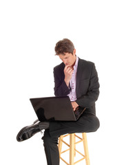 Puzzled young business man sitting and wondering