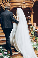 bride and groom holding hands and walking down the aisle at wedding ceremony indoors. walking on old wooden stairs