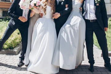 gorgeous bride with peony bouquet and stylish groom posing in sunny garden with bridesmaids and...