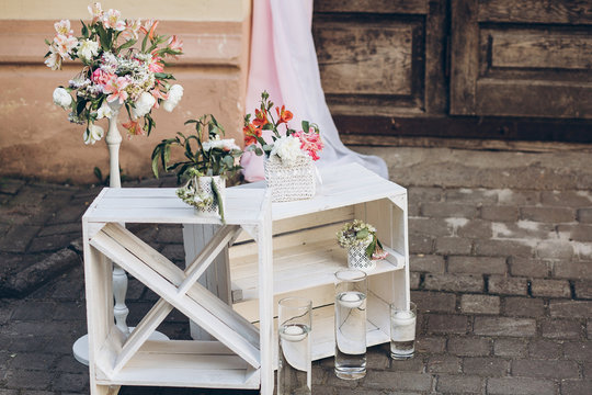 rustic wedding photo zone.  white boxes with flowers and candles at stylish wedding photo booth on background wooden barn doors with fabric and. shabby chic. luxury arrangments