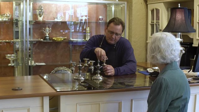 Customer and silversmith talking about a candelabra