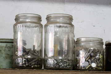 Metal screws in storage containers. Shelf locksmith workshop with parts for mechanical repairs.