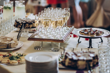 stylish champagne glasses and food  appetizers on table at wedding reception. luxury catering at...