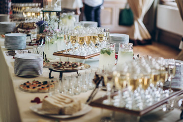 stylish champagne glasses and food  appetizers on table at wedding reception. luxury catering at celebrations. serving food and drinks at events concept - obrazy, fototapety, plakaty