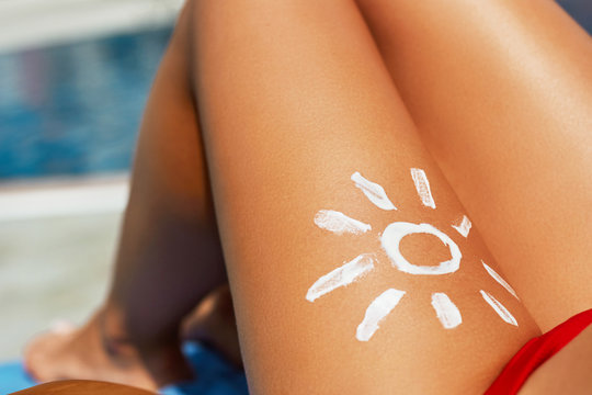 Portrait of gorgeous woman in bikini with the drawn sun on a leg.Sunscream