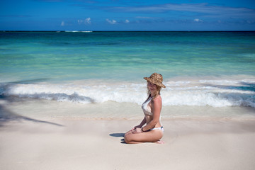 Fototapeta na wymiar Young girl in straw hat on the sandy beach
