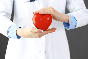 Female doctor with stethoscope holding heart in her arms. Healthcare and cardiology concept  in...