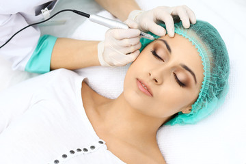Professional beautician doing eyebrow tattoo at woman face. Permanent brow makeup in beauty salon, closeup.  Cosmetology treatment