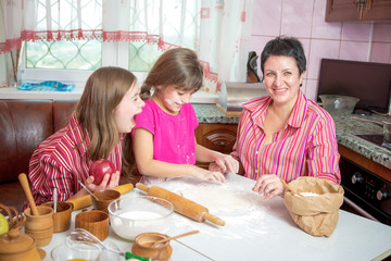 Mom teaching her two daughters cooking on the kitchen.