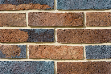 Tiles of house facade, gray and brown brick wall background.