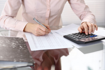 Female bookkeeper or financial inspector  making report, calculating or checking balance. Internal Revenue Service checking financial document. Audit concept in business