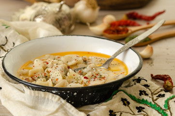 Turkish Manti  on plate with red pepper, tomatoes sauce, yogurt and garlic