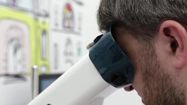 Man looks in apparatus for the treatment of spasm of accommodation, amblyopia and binocular vision disorders. Patient in ophthalmology clinic