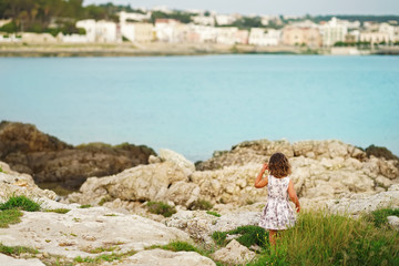 Fototapeta na wymiar Little girl on the background of Mediterranean rocks