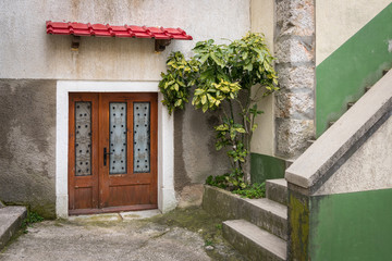 Entrance of a house in Beli, red canopy on a cloudy day in spring