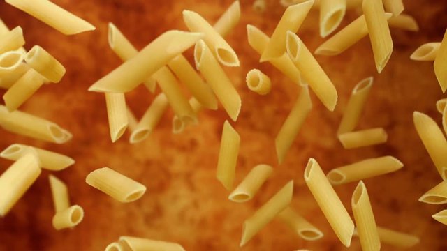 Pasta Penne flying in the air on a red background in slow motion