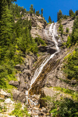 Ein Wasserfall stürzt einen hohen Felsen im Gebirge hinab