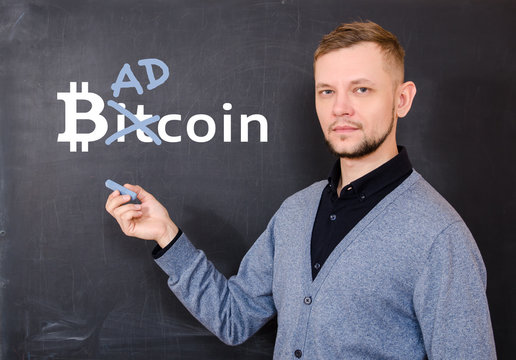 Man near a black school board on which is written bitkoin,  part of the word Bitcoin is replaced by Bad